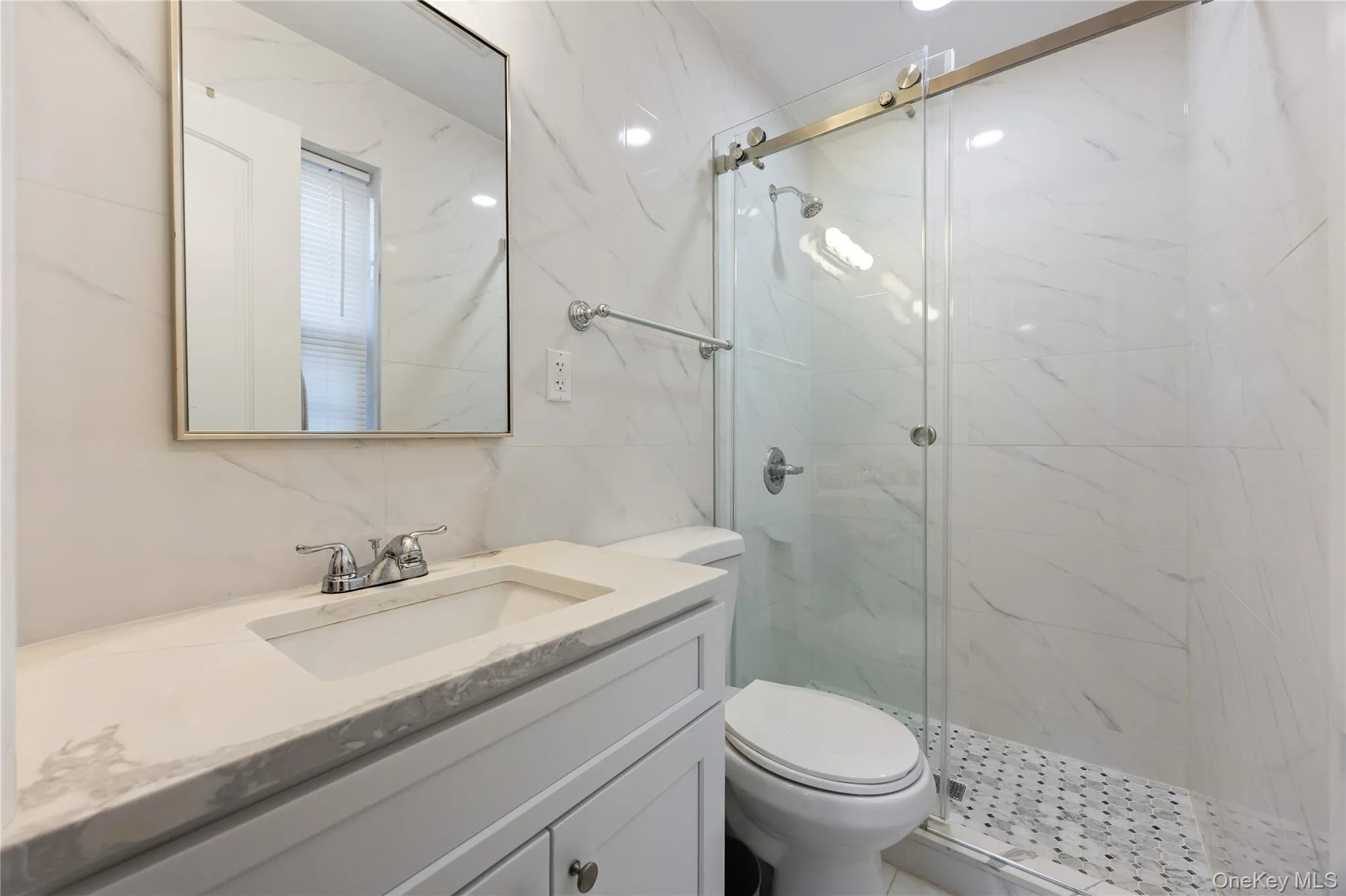 Bathroom with vanity, a marble finish shower, and tile walls Bathroom with vanity, a marble finish shower, and tile walls