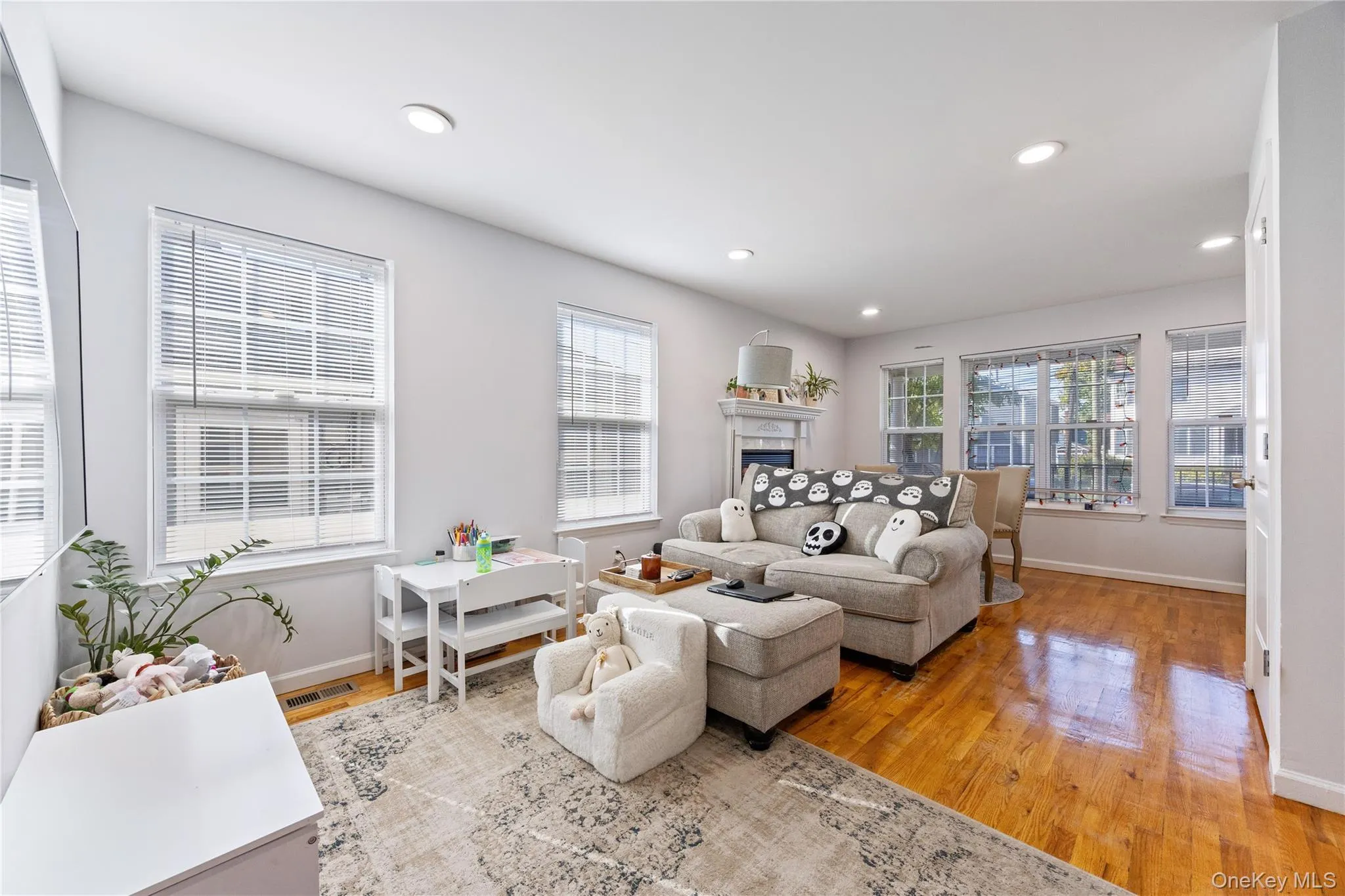 Living room with light wood-style floors, recessed lighting, and a tiled fireplace Living room with light wood-style floors, recessed lighting, and a tiled fireplace
