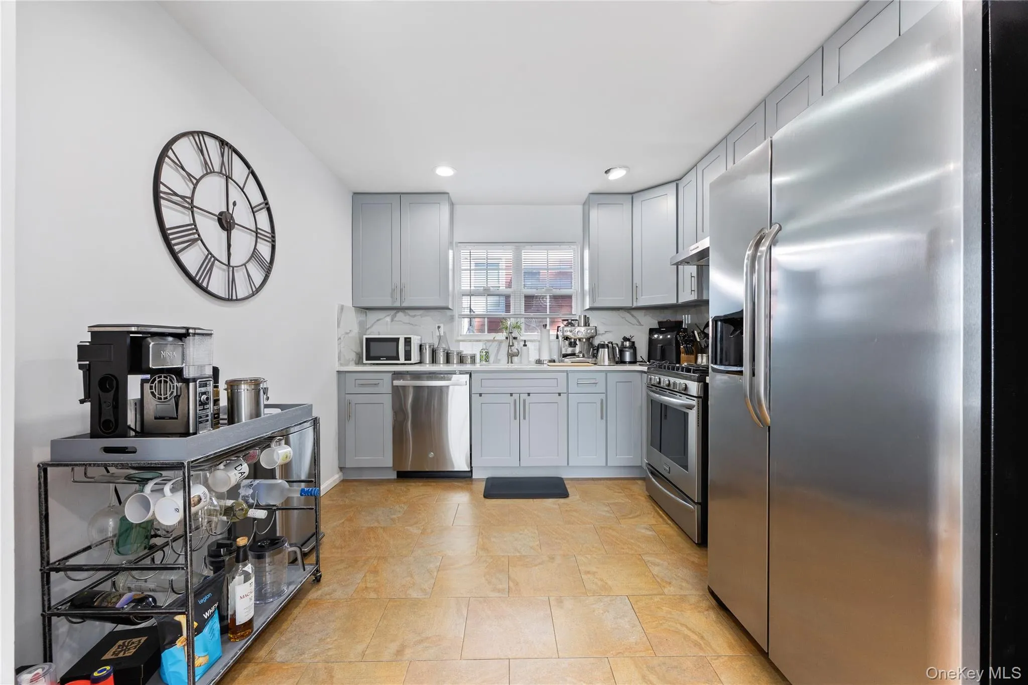 Kitchen featuring appliances with stainless steel finishes, light countertops, recessed lighting, gray cabinets, and decorative backsplash Kitchen featuring appliances with stainless steel finishes, light countertops, recessed lighting, gray cabinets, and decorative backsplash