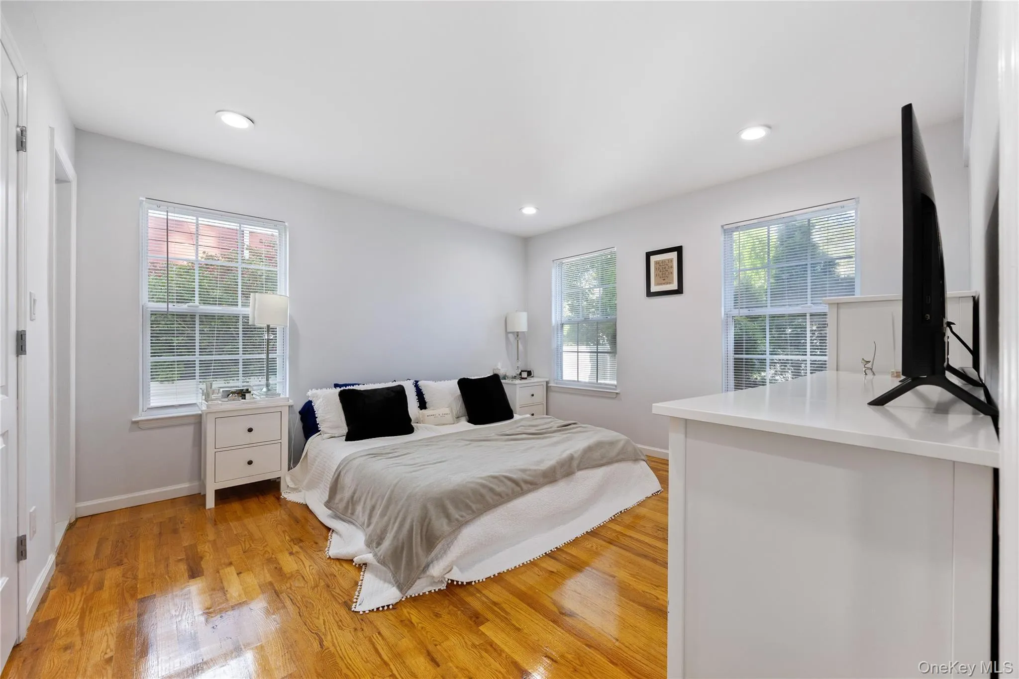 Bedroom with light wood-type flooring, multiple windows, and recessed lighting Bedroom with light wood-type flooring, multiple windows, and recessed lighting