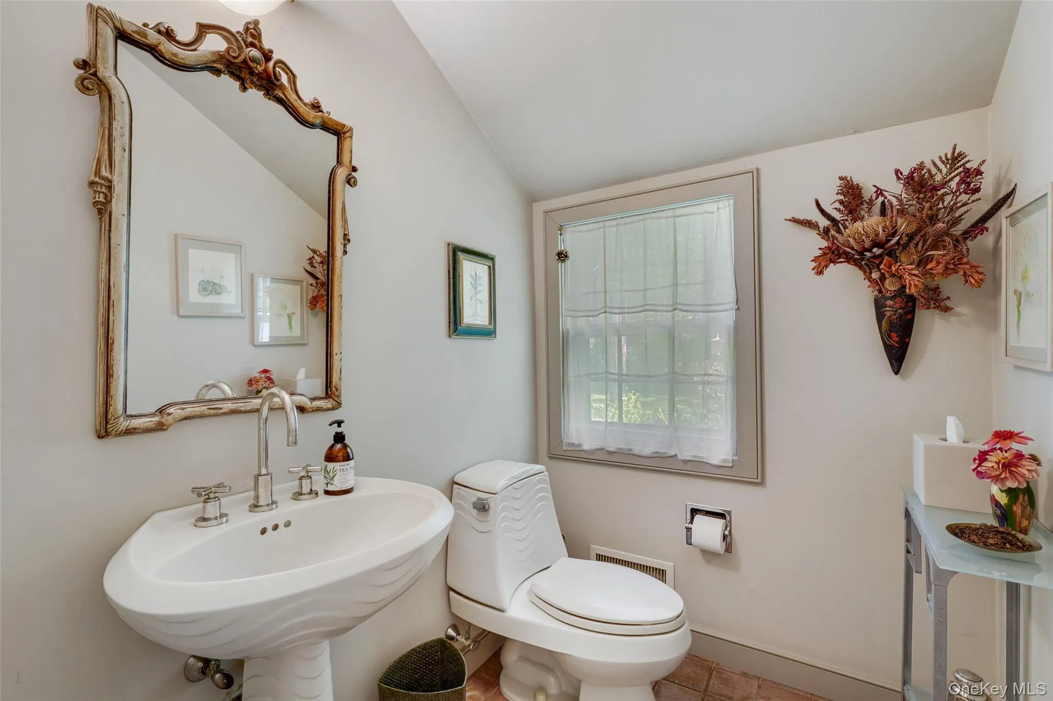 Bathroom with visible vents, toilet, a sink, baseboards, and vaulted ceiling Bathroom with visible vents, toilet, a sink, baseboards, and vaulted ceiling