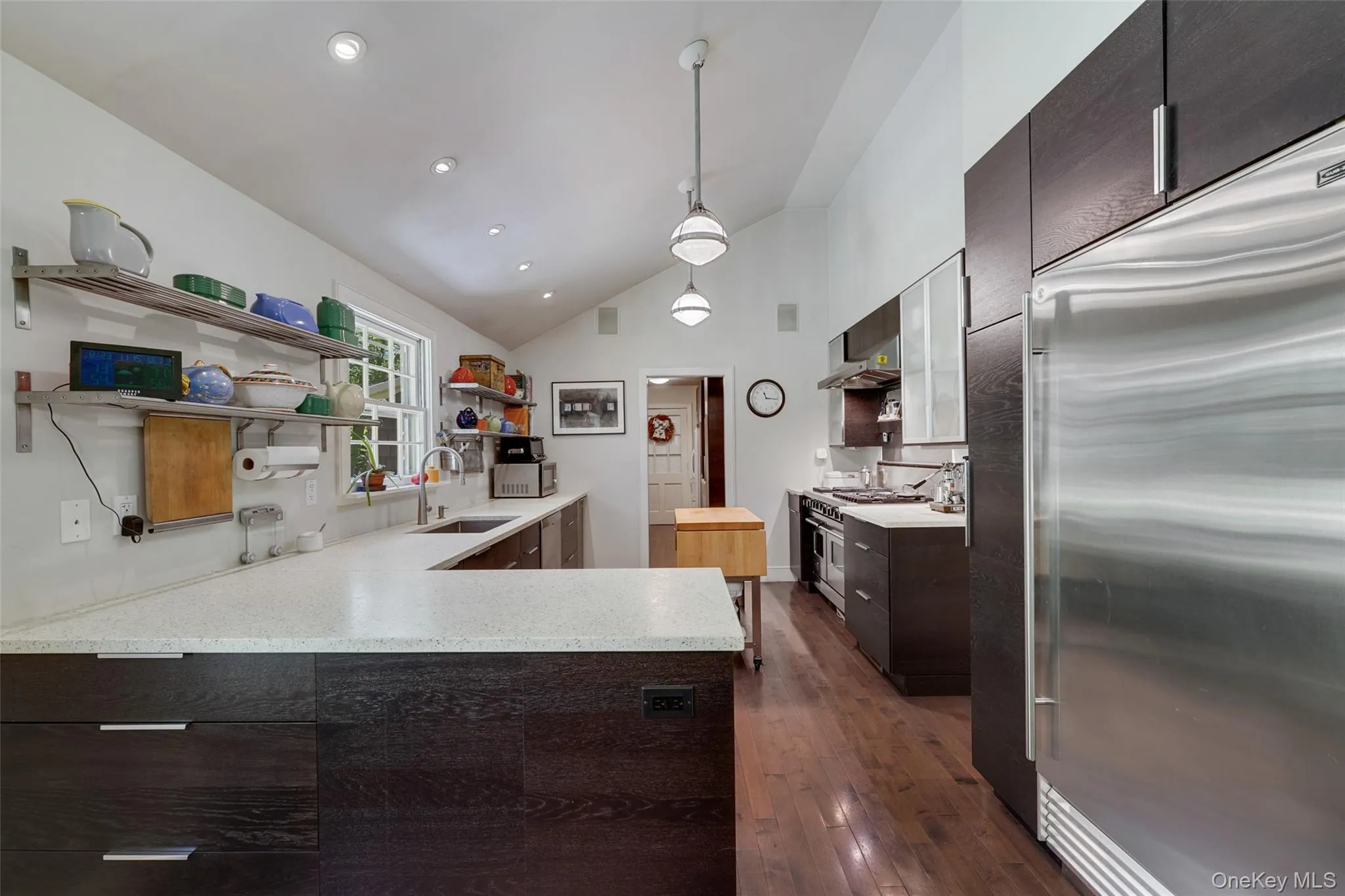 Kitchen with open shelves, a sink, vaulted ceiling, wall chimney exhaust hood, and premium appliances Kitchen with open shelves, a sink, vaulted ceiling, wall chimney exhaust hood, and premium appliances