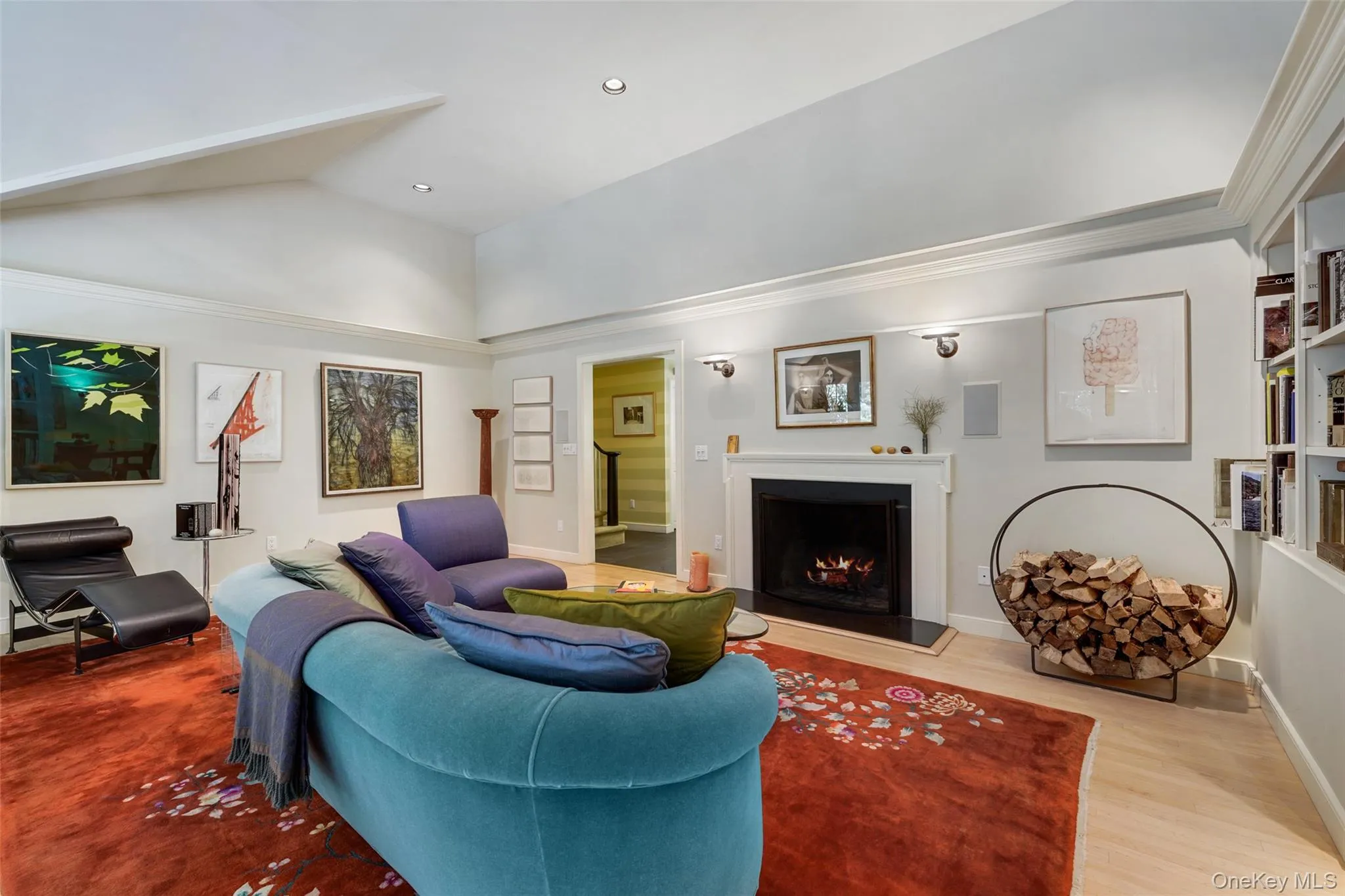Living area featuring lofted ceiling, wood finished floors, baseboards, and a lit fireplace Living area featuring lofted ceiling, wood finished floors, baseboards, and a lit fireplace