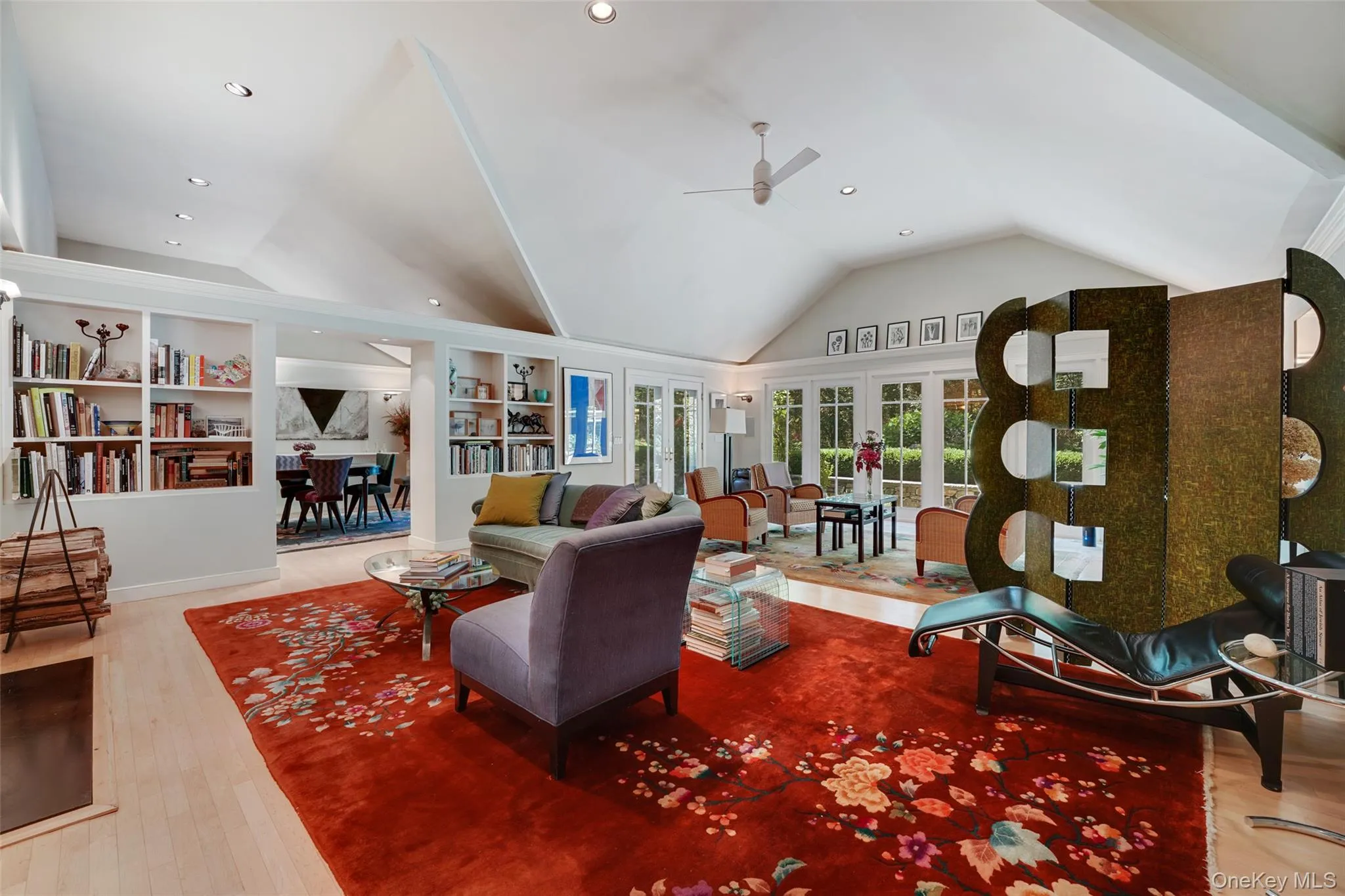 Living room with a ceiling fan, built in features, wood finished floors, recessed lighting, and vaulted ceiling Living room with a ceiling fan, built in features, wood finished floors, recessed lighting, and vaulted ceiling