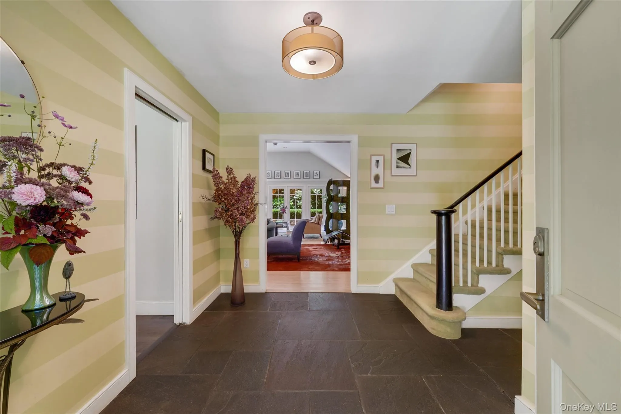 Foyer entrance featuring stairway, stone finish floor, french doors, and baseboards Foyer entrance featuring stairway, stone finish floor, french doors, and baseboards
