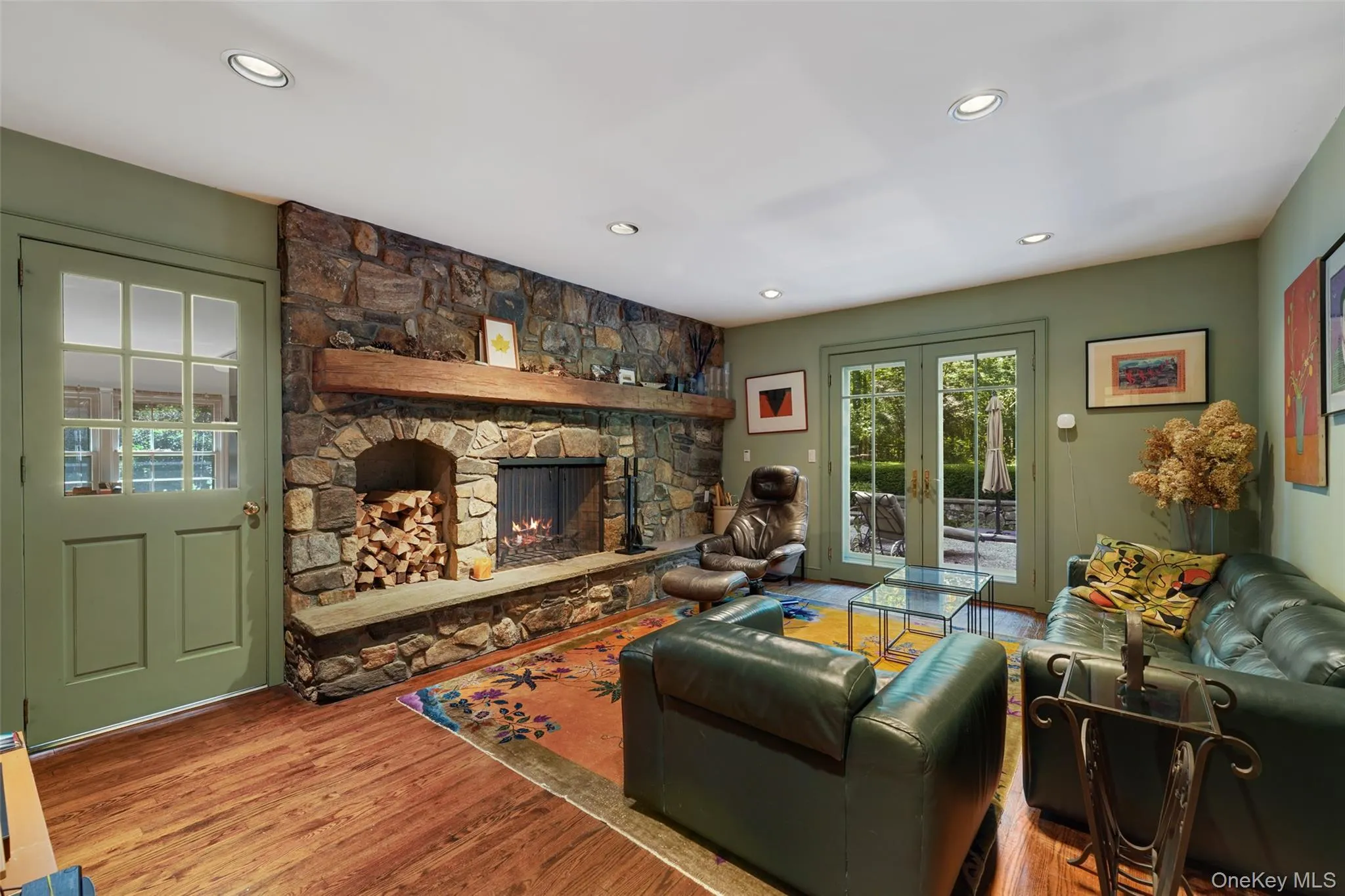 Living room featuring recessed lighting, a stone fireplace, and wood finished floors Living room featuring recessed lighting, a stone fireplace, and wood finished floors