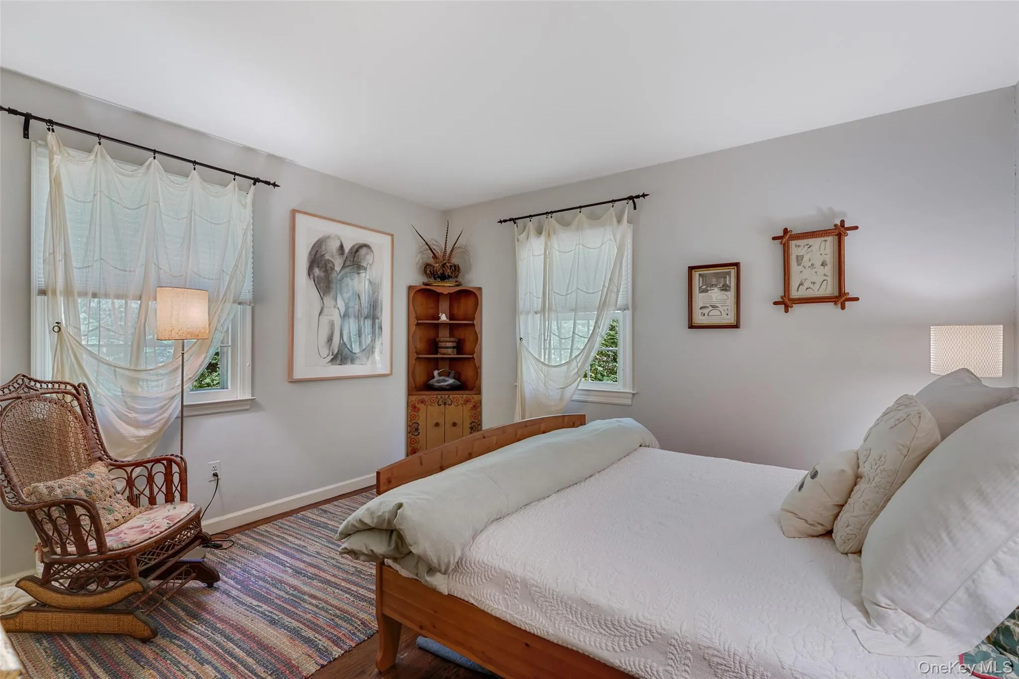 Bedroom featuring multiple windows, wood finished floors, and baseboards Bedroom featuring multiple windows, wood finished floors, and baseboards