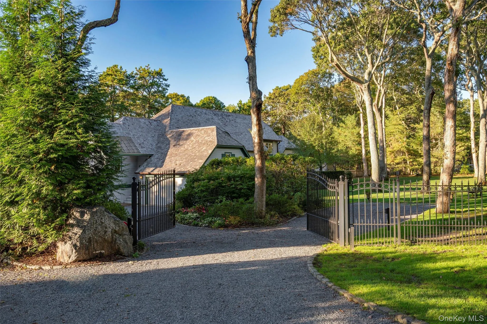 View of front facade featuring a gate and a shingled roof View of front facade featuring a gate and a shingled roof