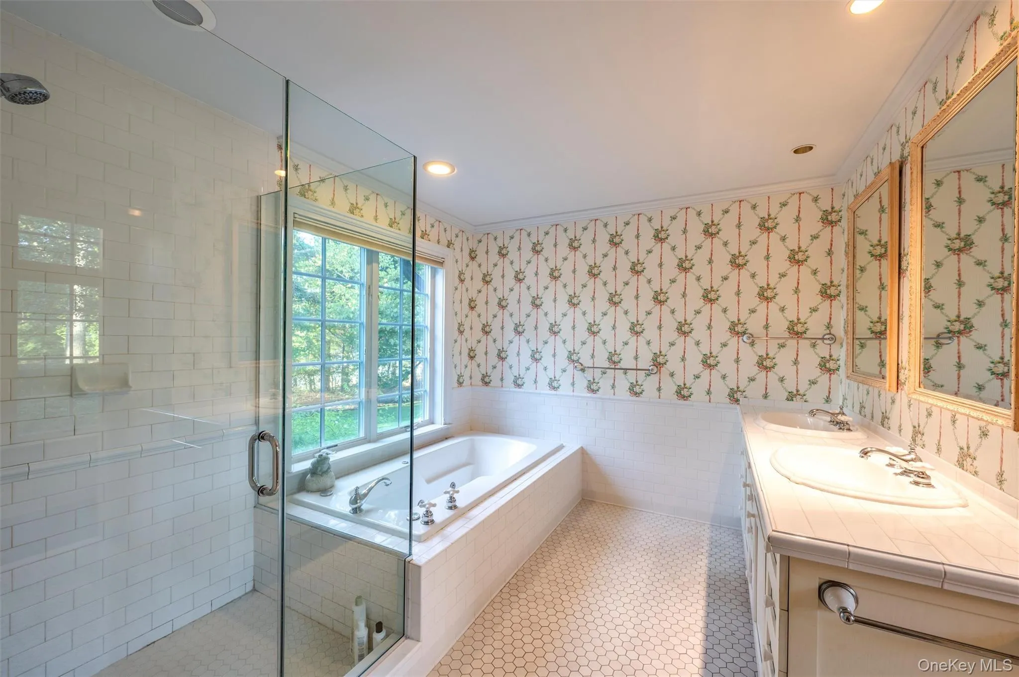 Full bath featuring wallpapered walls, tile walls, a wainscoted wall, a stall shower, and a garden tub Full bath featuring wallpapered walls, tile walls, a wainscoted wall, a stall shower, and a garden tub