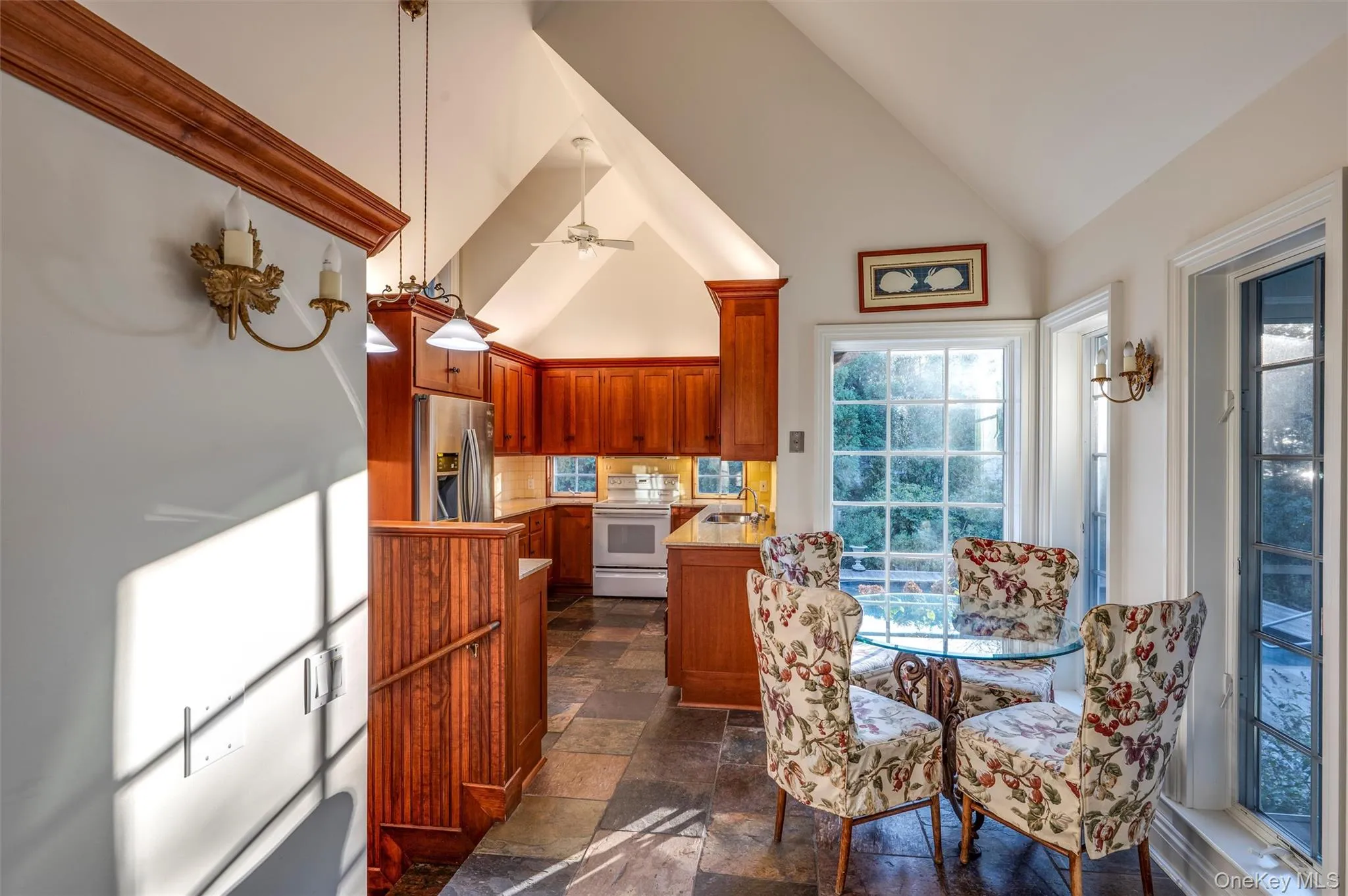 Dining area with high vaulted ceiling, ceiling fan, and stone tile floors Dining area with high vaulted ceiling, ceiling fan, and stone tile floors