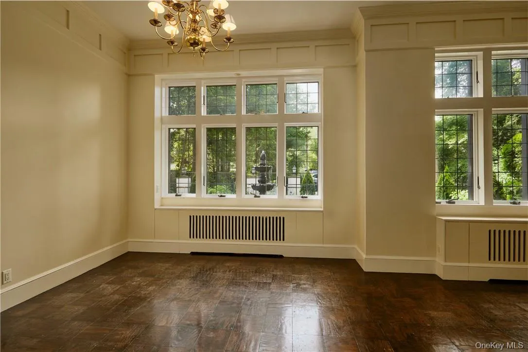Empty room featuring an inviting chandelier, plenty of natural light, ornamental molding, and radiator Empty room featuring an inviting chandelier, plenty of natural light, ornamental molding, and radiator