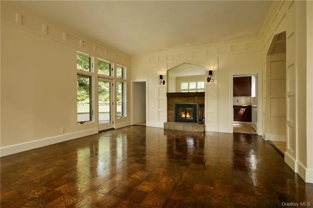 Unfurnished living room featuring dark parquet floors and a fireplace Unfurnished living room featuring dark parquet floors and a fireplace