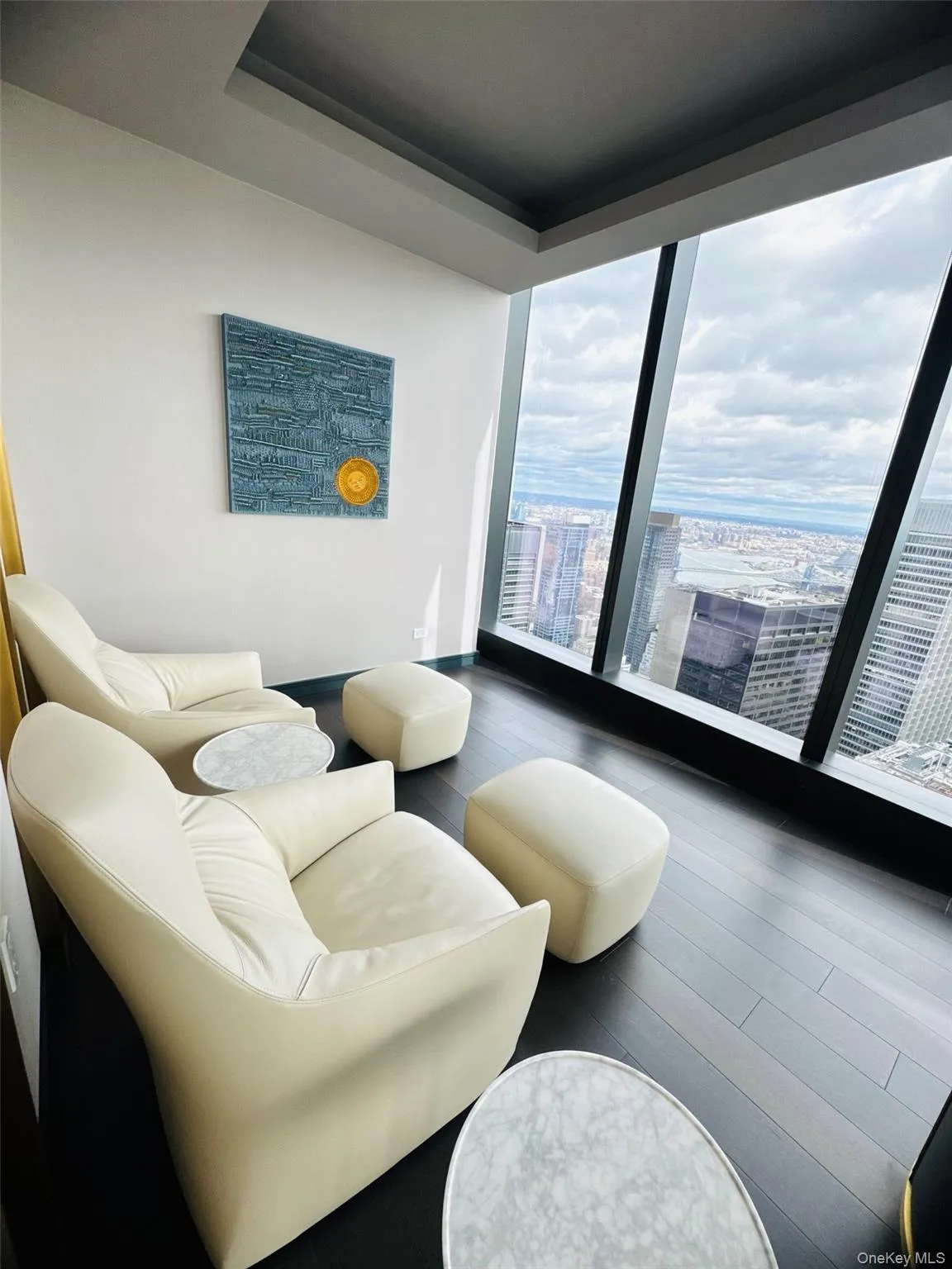 Living area with a view of city, wood finished floors, a wall of windows, and a raised ceiling Living area with a view of city, wood finished floors, a wall of windows, and a raised ceiling