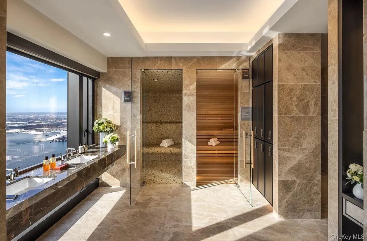 Bathroom featuring tile walls, double vanity, a stall shower, recessed lighting, and a water view Bathroom featuring tile walls, double vanity, a stall shower, recessed lighting, and a water view