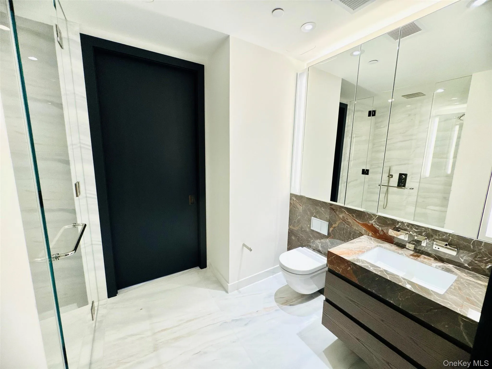 Bathroom with marble tiled floors, recessed lighting, a marble finish shower, vanity, and tasteful backsplash Bathroom with marble tiled floors, recessed lighting, a marble finish shower, vanity, and tasteful backsplash