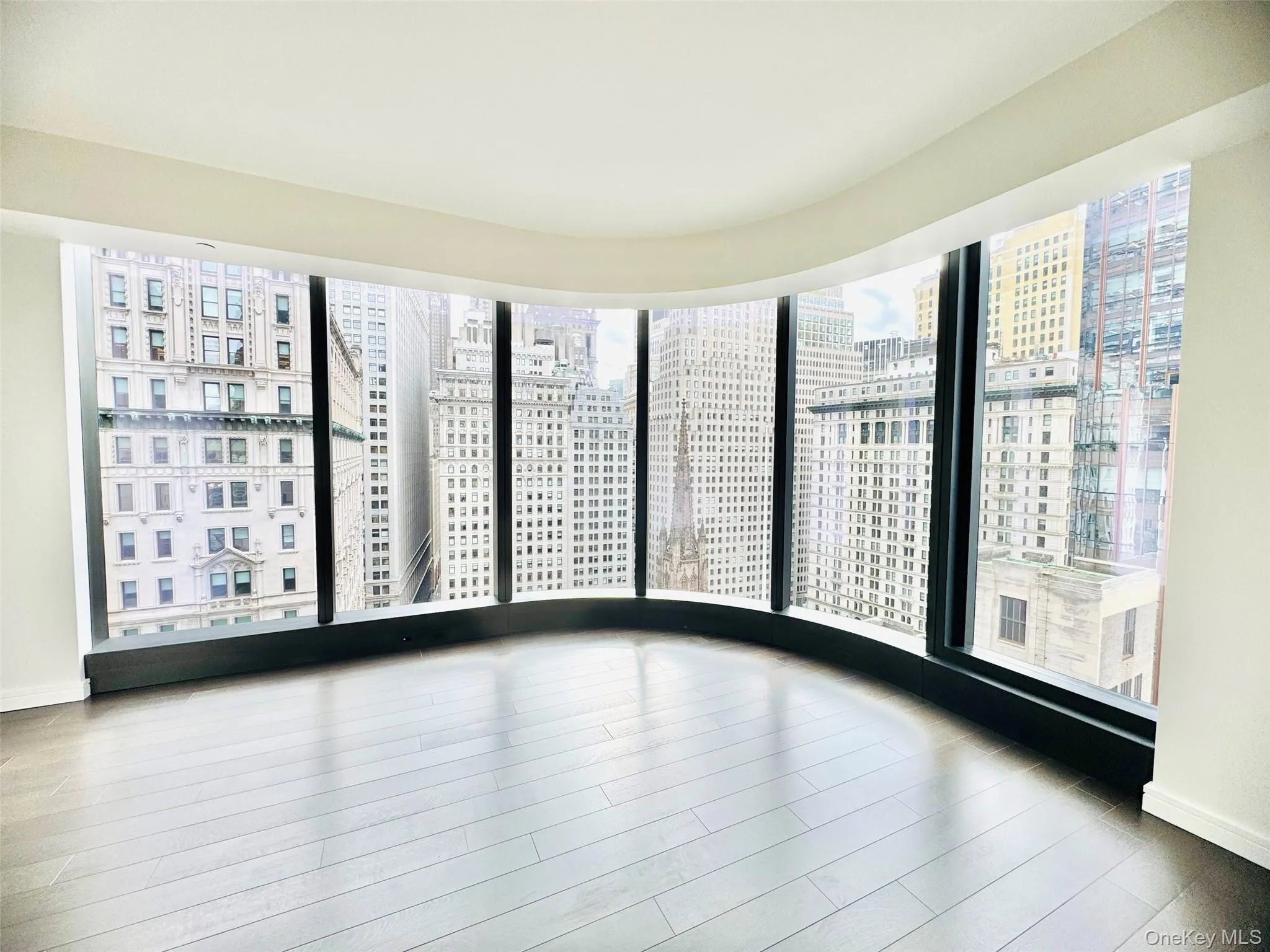 Unfurnished room featuring a view of city, plenty of natural light, and wood finished floors Unfurnished room featuring a view of city, plenty of natural light, and wood finished floors