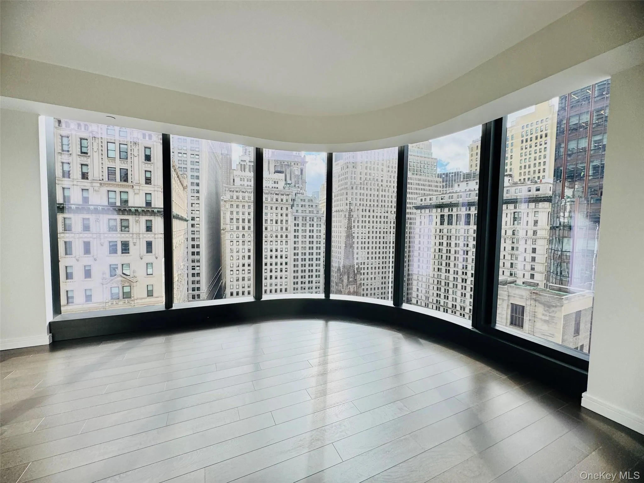 Spare room with a view of city, wood finished floors, and floor to ceiling windows Spare room with a view of city, wood finished floors, and floor to ceiling windows