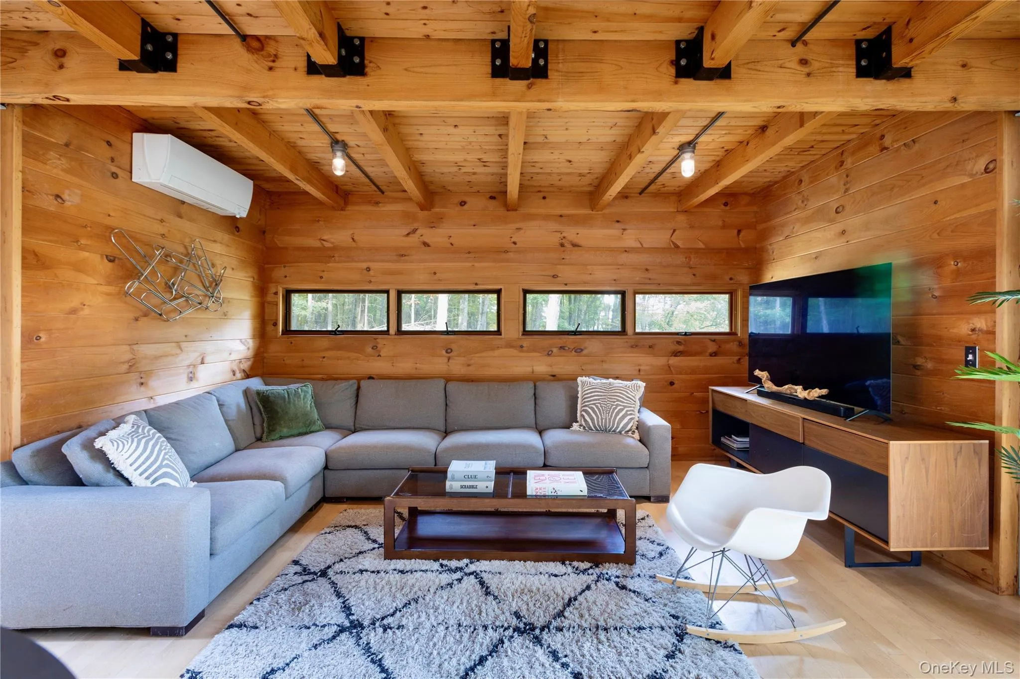 Living area with wood walls, a wood ceiling with exposed beams, wood finished floors, healthy amount of natural light, and a wall mounted AC Living area with wood walls, a wood ceiling with exposed beams, wood finished floors, healthy amount of natural light, and a wall mounted AC