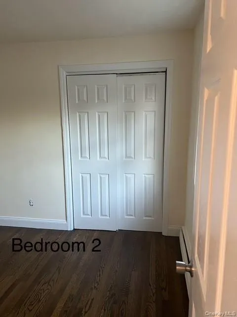 Unfurnished bedroom with dark wood-style floors and a closet Unfurnished bedroom with dark wood-style floors and a closet