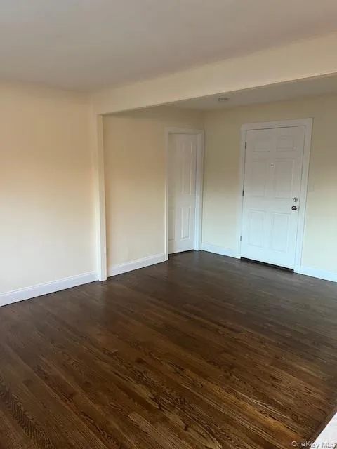Spare room featuring dark wood-style floors and baseboards Spare room featuring dark wood-style floors and baseboards