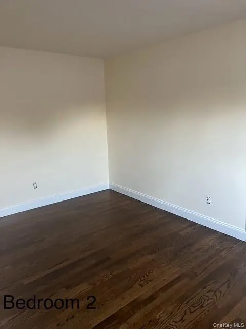 Unfurnished room featuring baseboards and dark wood-style flooring Unfurnished room featuring baseboards and dark wood-style flooring
