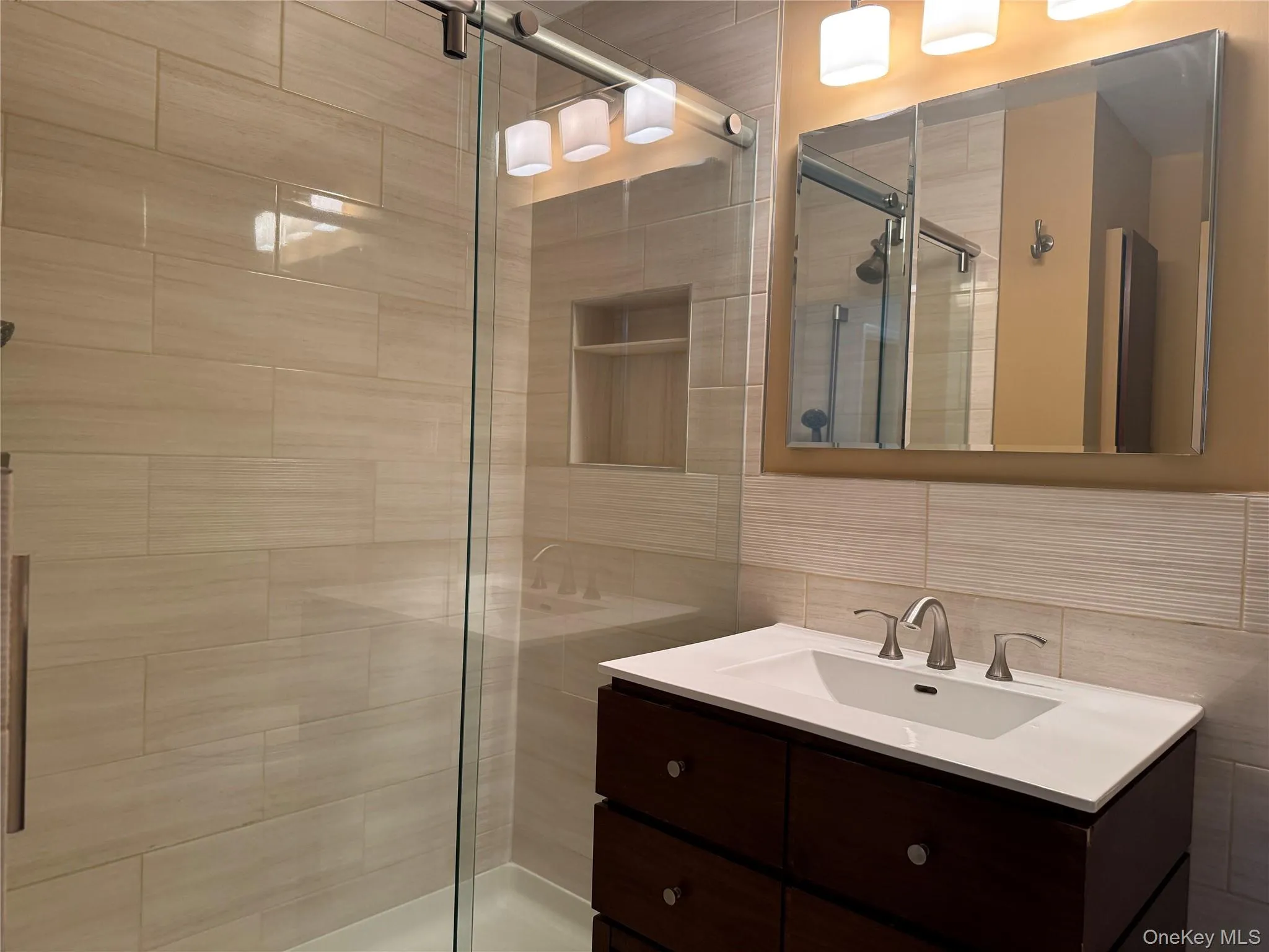 Bathroom with vanity, a stall shower, and tile walls Bathroom with vanity, a stall shower, and tile walls