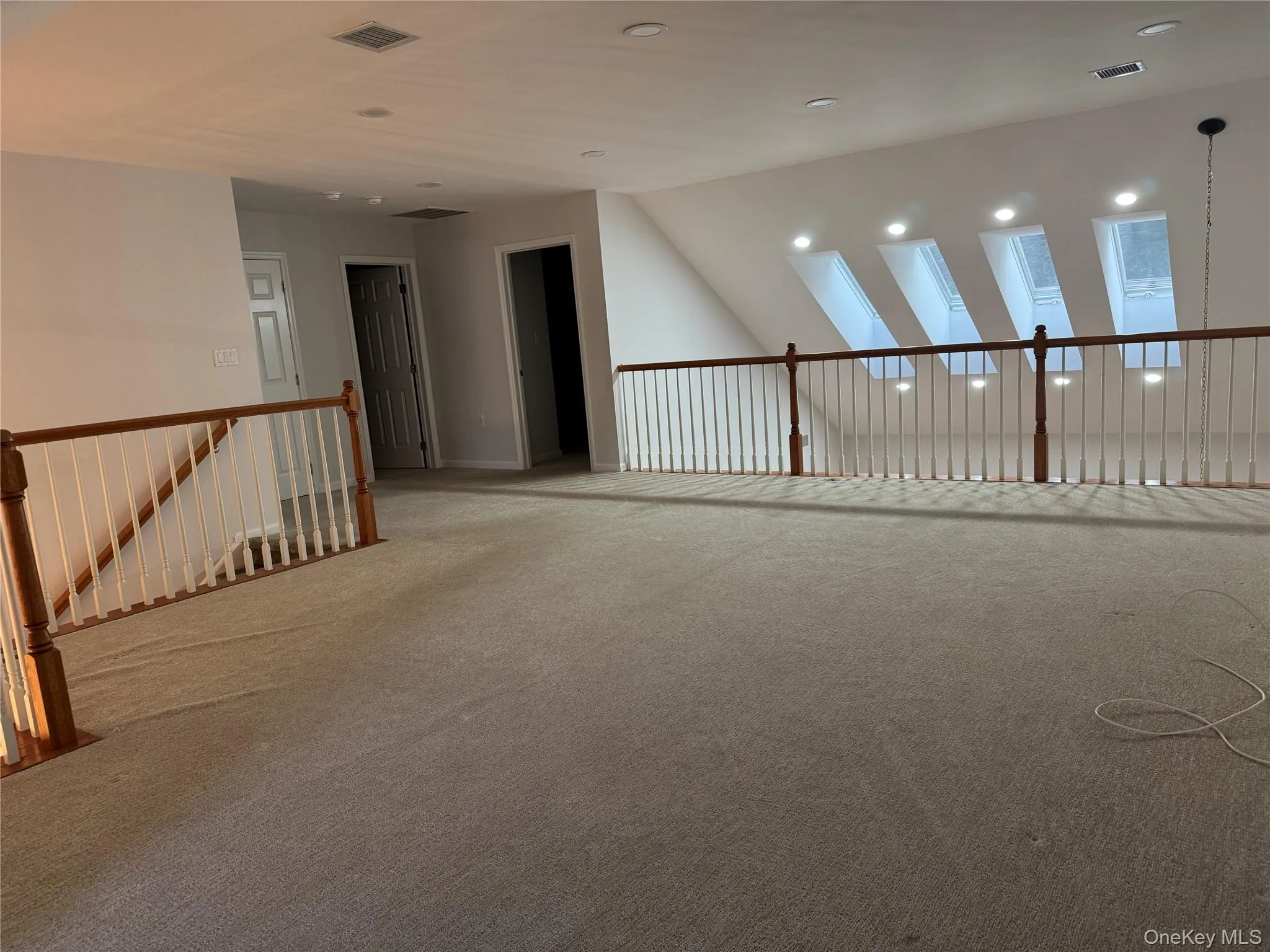 Carpeted empty room featuring vaulted ceiling and recessed lighting Carpeted empty room featuring vaulted ceiling and recessed lighting