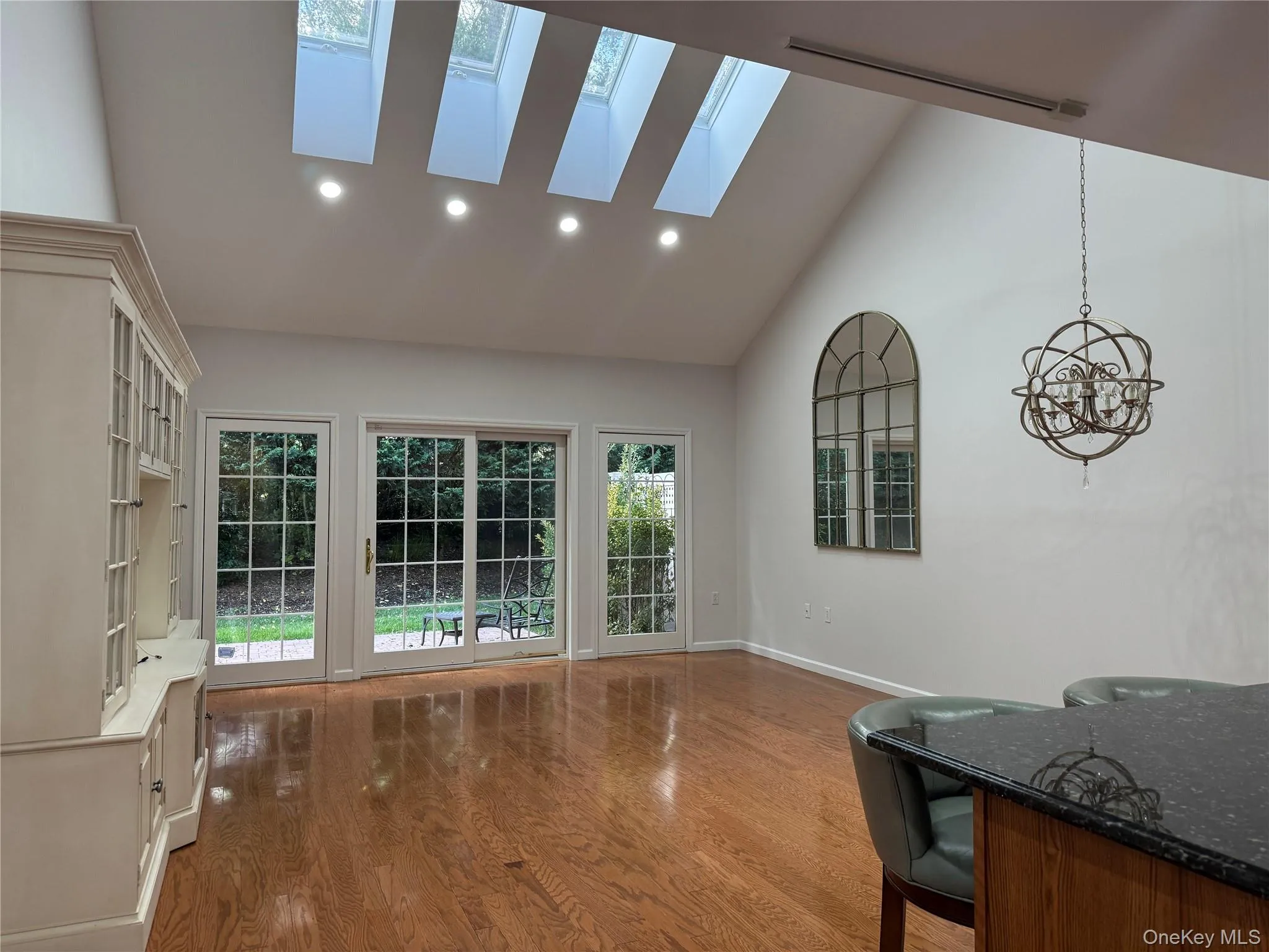 Living area featuring high vaulted ceiling, dark wood finished floors, recessed lighting, a skylight, and a chandelier Living area featuring high vaulted ceiling, dark wood finished floors, recessed lighting, a skylight, and a chandelier