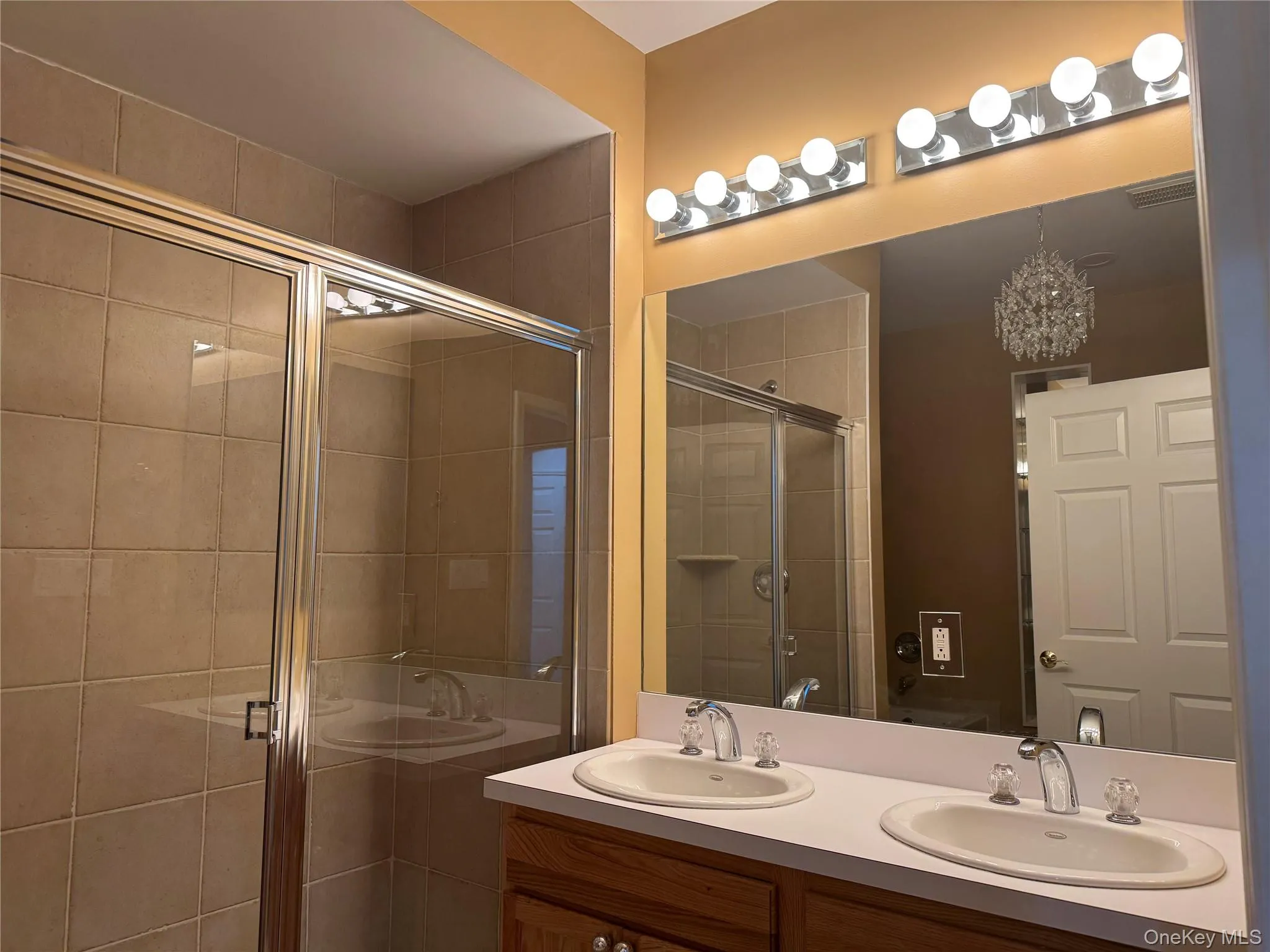 Full bath with double vanity, a stall shower, and a chandelier Full bath with double vanity, a stall shower, and a chandelier