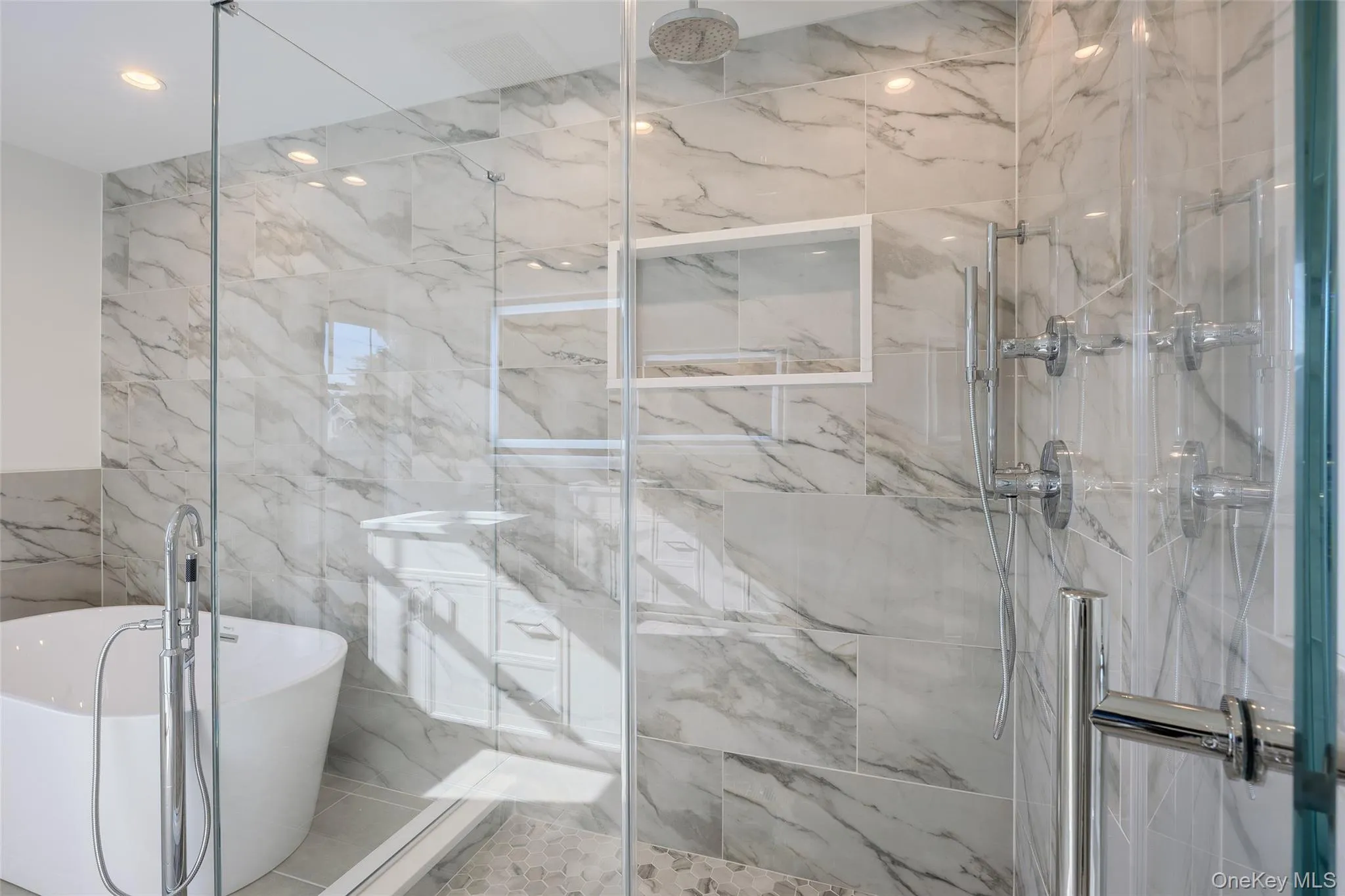 Bathroom with a freestanding bath, tile walls, and a marble finish shower Bathroom with a freestanding bath, tile walls, and a marble finish shower