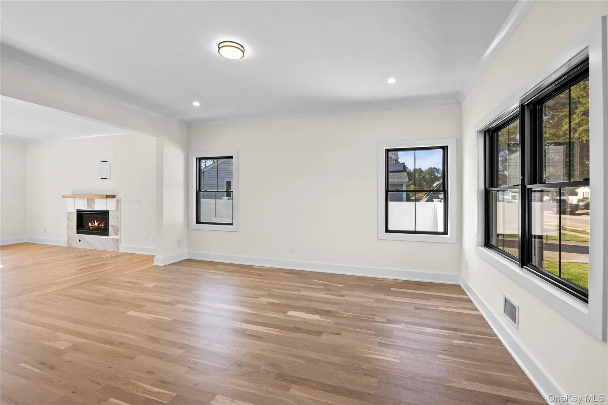 Unfurnished living room featuring a premium fireplace, light wood-style floors, crown molding, and recessed lighting Unfurnished living room featuring a premium fireplace, light wood-style floors, crown molding, and recessed lighting