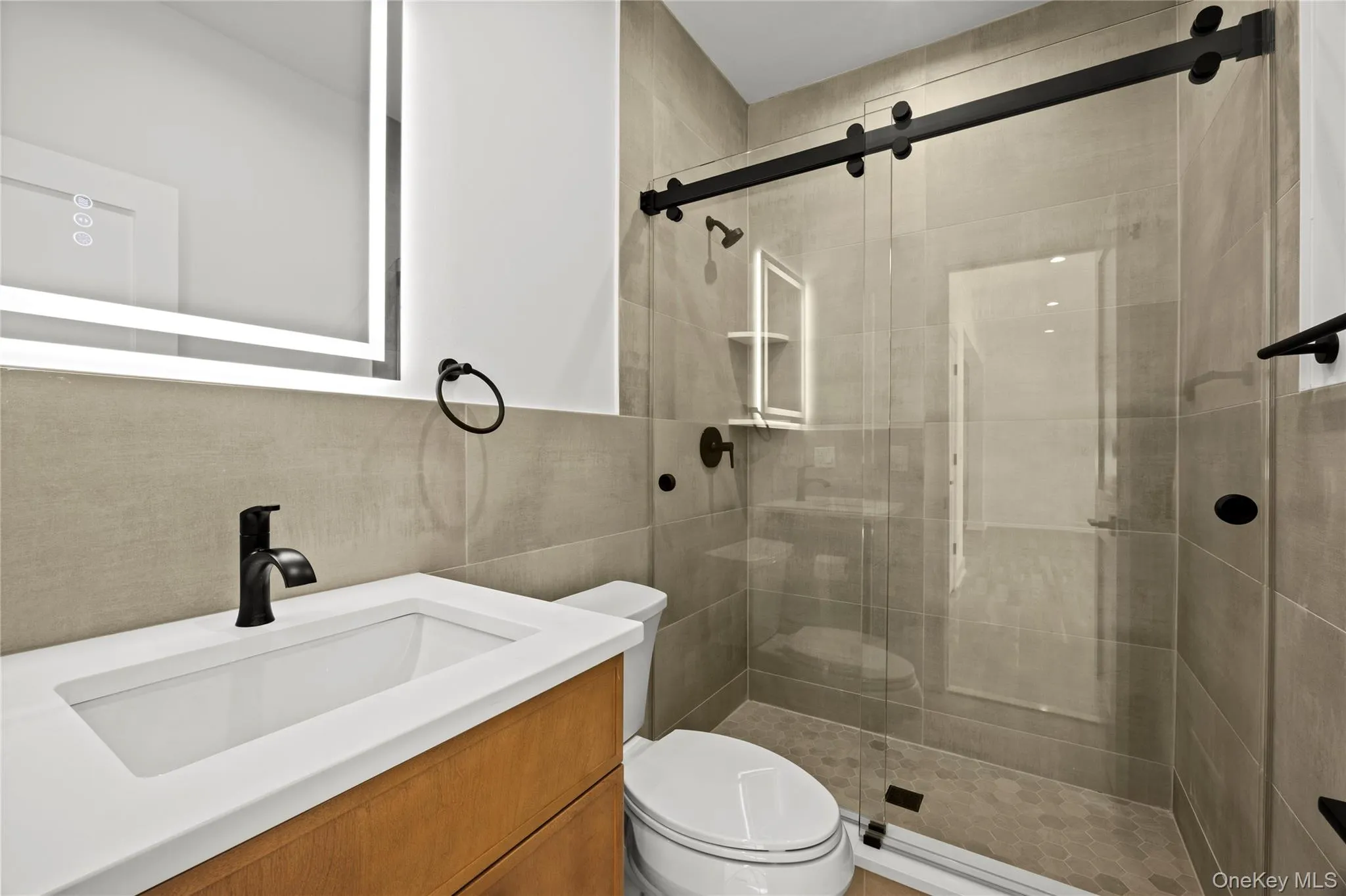 Bathroom with vanity, a shower stall, and tile walls Bathroom with vanity, a shower stall, and tile walls