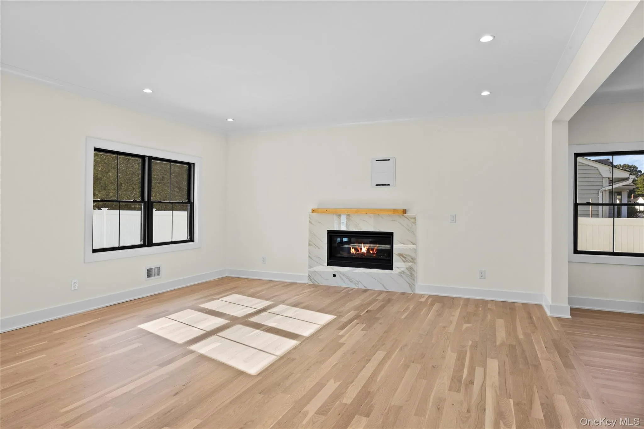 Unfurnished living room with a premium fireplace, recessed lighting, light wood-style flooring, and ornamental molding Unfurnished living room with a premium fireplace, recessed lighting, light wood-style flooring, and ornamental molding