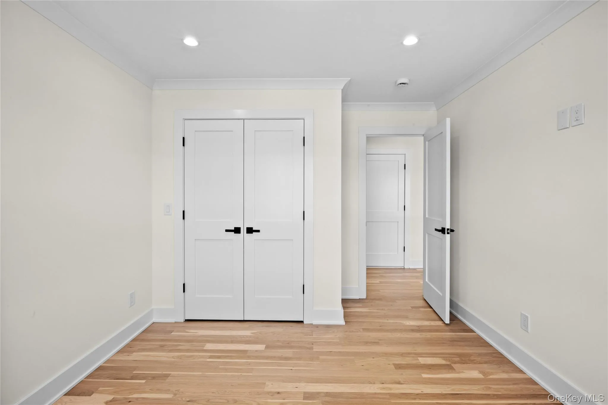 Unfurnished bedroom with light wood-type flooring, ornamental molding, a closet, and recessed lighting Unfurnished bedroom with light wood-type flooring, ornamental molding, a closet, and recessed lighting