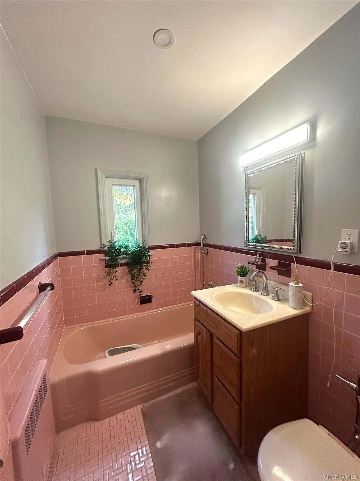 Bathroom with tile walls, a wainscoted wall, a bath, radiator heating unit, and vanity Bathroom with tile walls, a wainscoted wall, a bath, radiator heating unit, and vanity