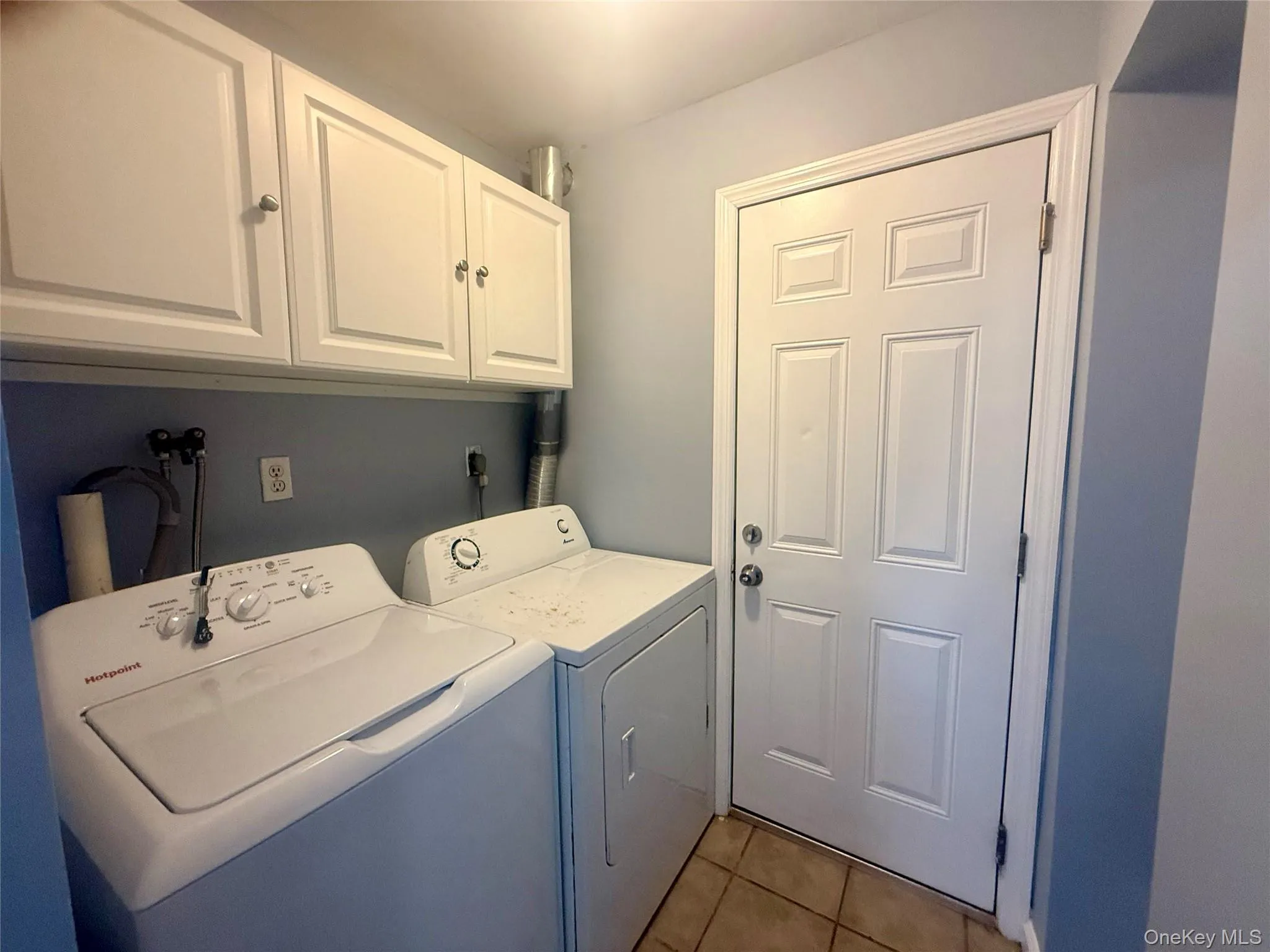 Laundry room with light tile patterned floors, cabinet space, and independent washer and dryer Laundry room with light tile patterned floors, cabinet space, and independent washer and dryer
