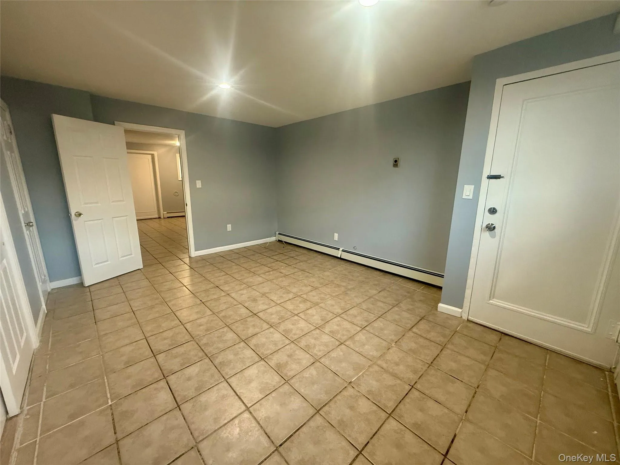 Empty room featuring a baseboard heating unit and light tile patterned floors Empty room featuring a baseboard heating unit and light tile patterned floors
