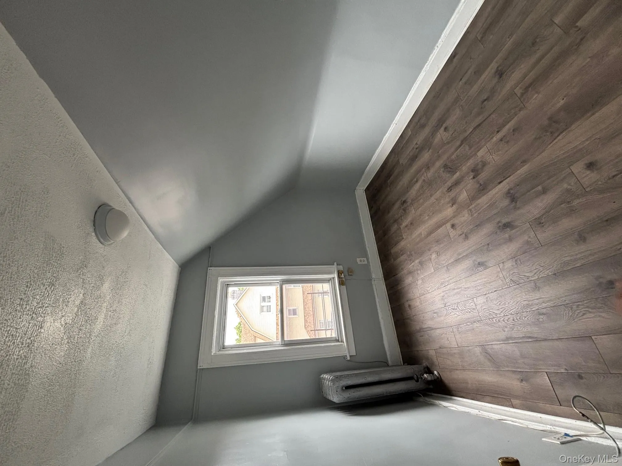 Bonus room featuring dark wood-style floors, radiator, a textured ceiling, and lofted ceiling Bonus room featuring dark wood-style floors, radiator, a textured ceiling, and lofted ceiling