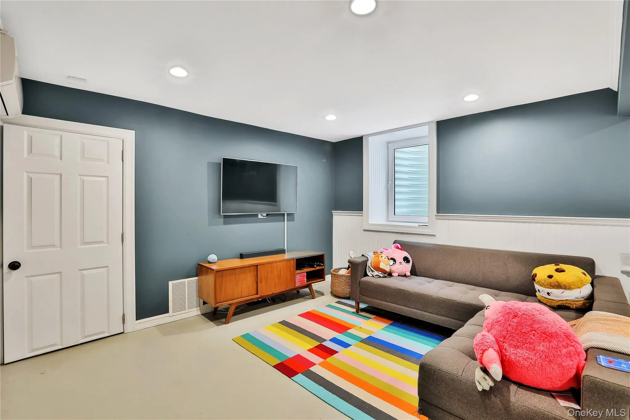 Finished basement featuring recessed lighting, finished concrete floors, a wall mounted AC, and a wainscoted wall Finished basement featuring recessed lighting, finished concrete floors, a wall mounted AC, and a wainscoted wall