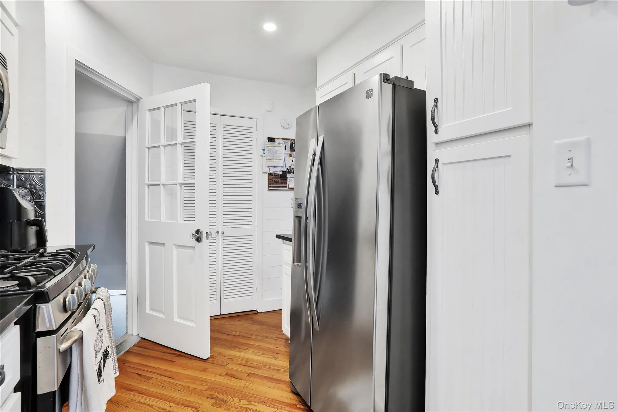Kitchen featuring stainless steel appliances, hardwood floors, white cabinets, and recessed lighting Kitchen featuring stainless steel appliances, hardwood floors, white cabinets, and recessed lighting