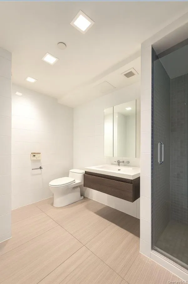 Bathroom featuring vanity, a shower stall, tile walls, and light tile patterned flooring Bathroom featuring vanity, a shower stall, tile walls, and light tile patterned flooring