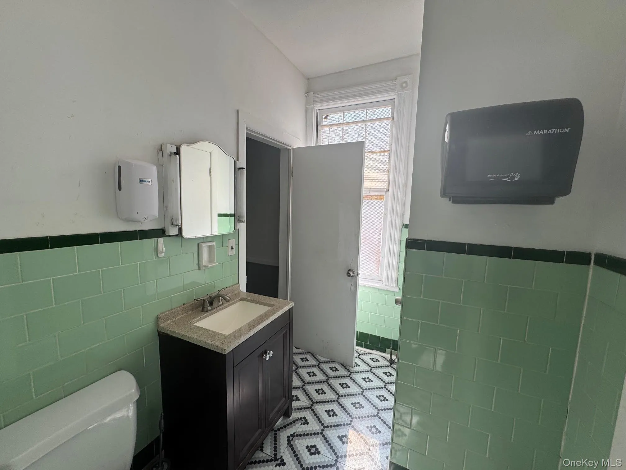Half bath featuring tile walls, vanity, and wainscoting Half bath featuring tile walls, vanity, and wainscoting