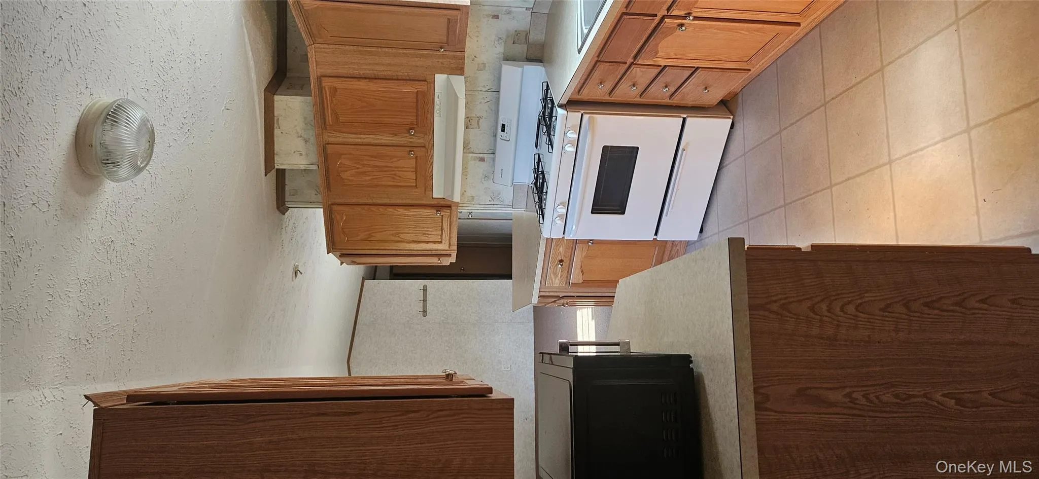 Kitchen featuring range, light countertops, brown cabinets, a textured ceiling, and light tile patterned floors Kitchen featuring range, light countertops, brown cabinets, a textured ceiling, and light tile patterned floors