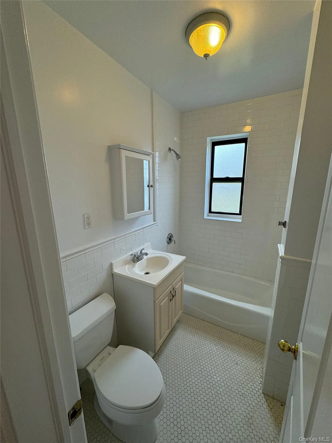 Full bathroom featuring tile walls, vanity, bathtub / shower combination, and a wainscoted wall Full bathroom featuring tile walls, vanity, bathtub / shower combination, and a wainscoted wall