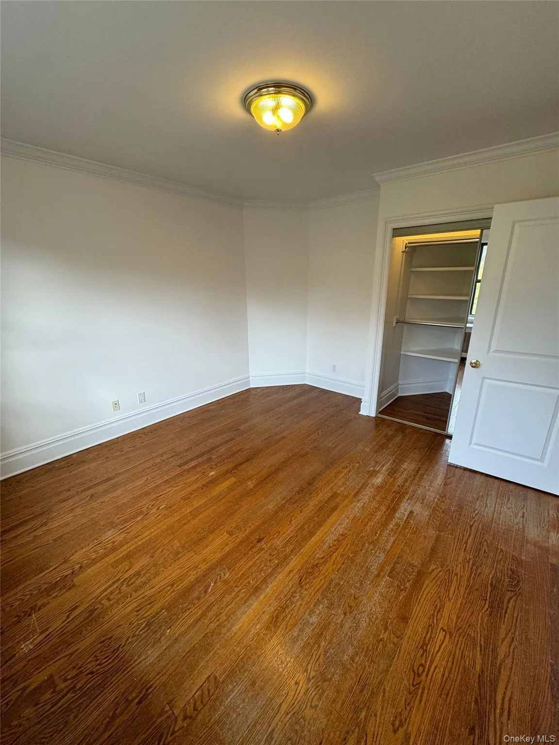 Unfurnished bedroom featuring crown molding and dark wood-type flooring Unfurnished bedroom featuring crown molding and dark wood-type flooring