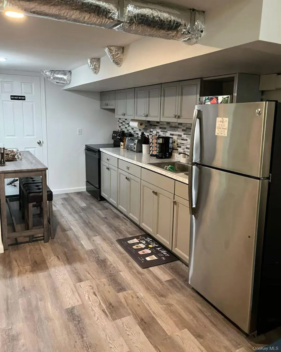 Kitchen with freestanding refrigerator, gray cabinets, black electric range oven, and light countertops Kitchen with freestanding refrigerator, gray cabinets, black electric range oven, and light countertops