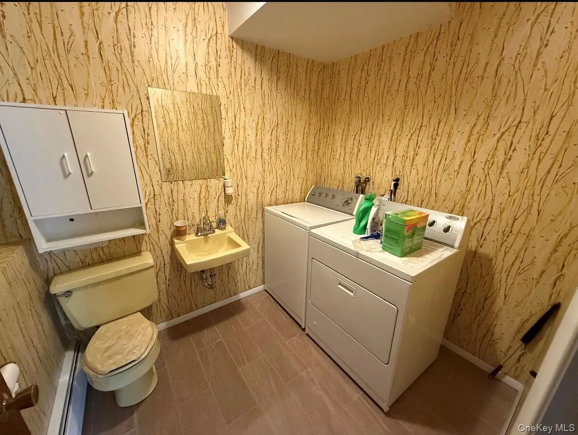 Laundry area with washer and clothes dryer and wallpapered walls Laundry area with washer and clothes dryer and wallpapered walls