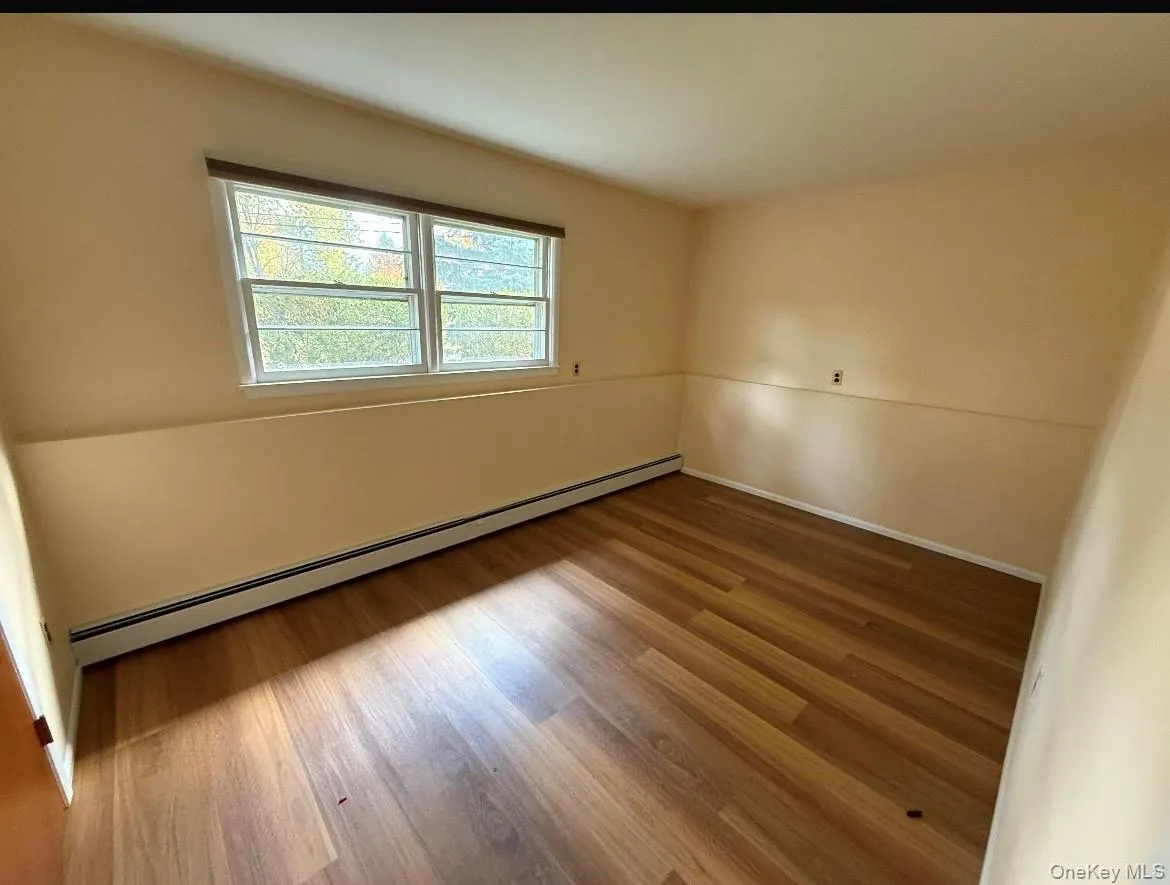 Empty room with baseboard heating and wood finished floors Empty room with baseboard heating and wood finished floors
