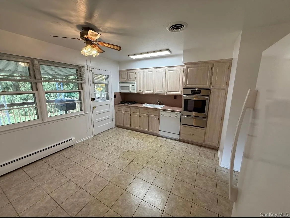 Kitchen with light brown cabinets, white appliances, a ceiling fan, light tile patterned floors, and a warming drawer Kitchen with light brown cabinets, white appliances, a ceiling fan, light tile patterned floors, and a warming drawer