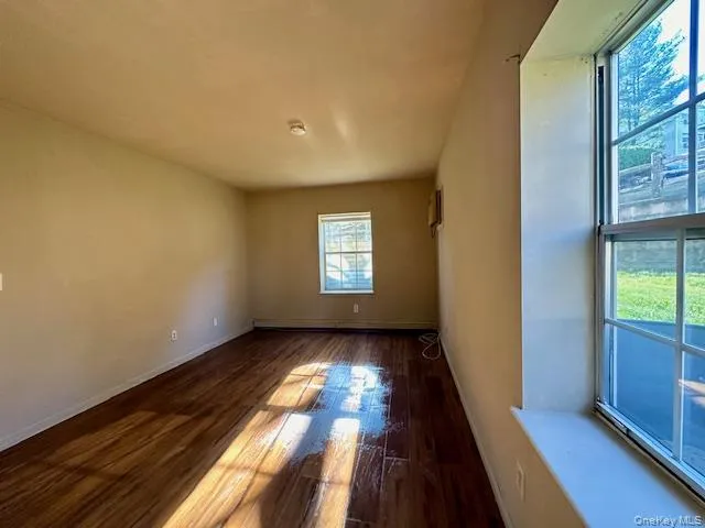 Empty room featuring dark wood-type flooring and baseboards Empty room featuring dark wood-type flooring and baseboards